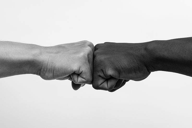 a black fist fist-bumping a white fist