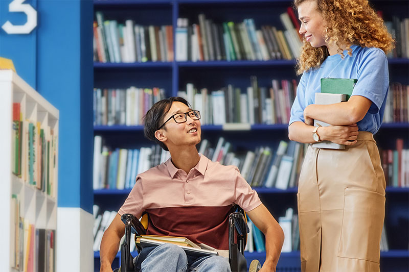 a person in a wheelchair conversing with a coworker.