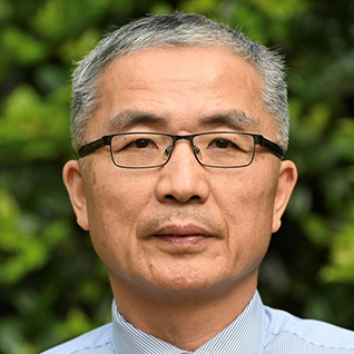 Chinese American Branch Chief Dr. Yuling Hong wearing a grey suit jacket, light blue shirt, and lavender tie in front of a grey background.