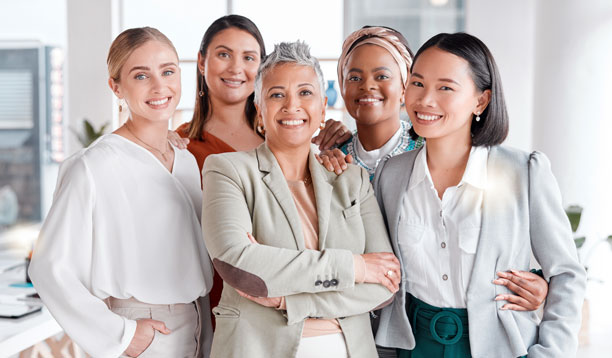 A group of women of varying ages and ethnicities smailing and looking at the camera.