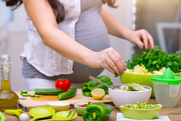 A pregnant person in a preparing food in the kitchen