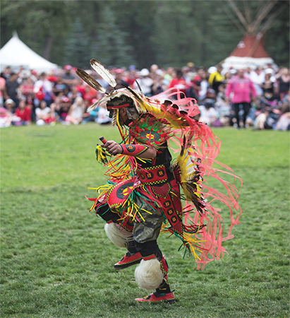 Native American man wearing full regalia dancing at a powwow.