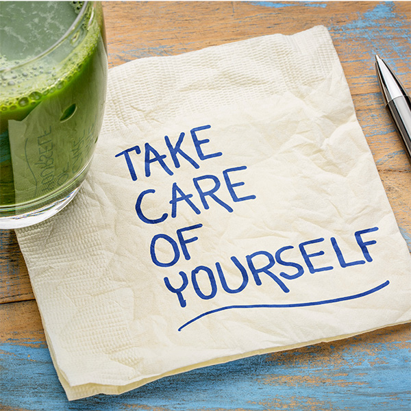 A napkin on a table with a note written on it saying take care of yourself