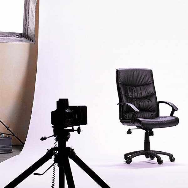 Camera on a tripod at a photoshoot of an office chair.