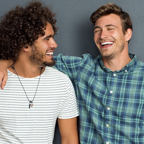 Two guys standing together smiling and laughing.