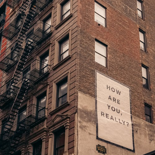 A billboard on the side of building that reads How are you really?