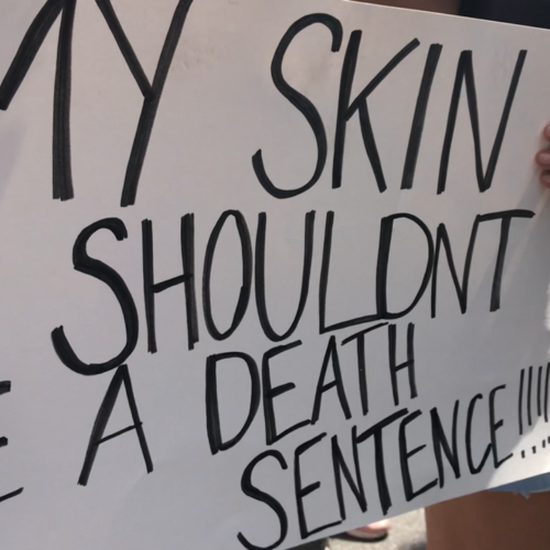 Close-up of a black and white sign that read My Skin Shouldn’t Be a Death Sentence