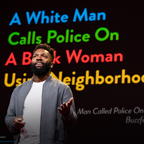 A bearded black man in front of a large screen with colorful letters that read A white man calls the police and A black woman