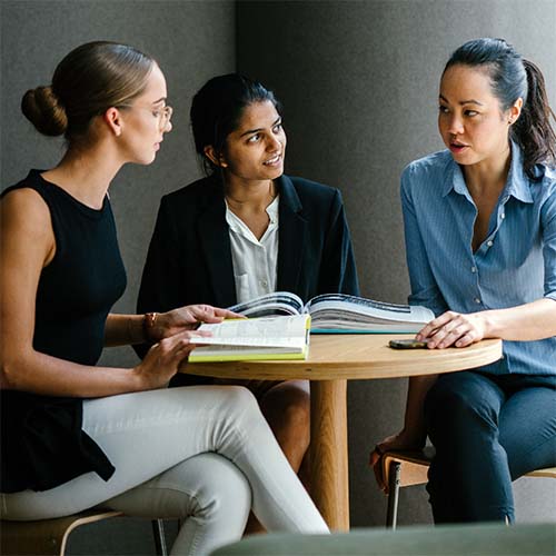 Three women sitting at table having a meeting.
