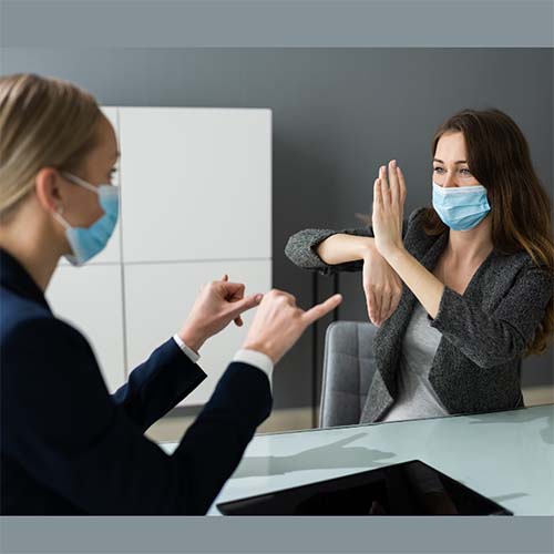 Two women wearing surgical masks having a meeting.