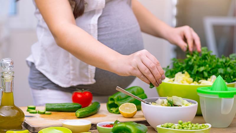 A pregnant person preparing food in the kitchen.