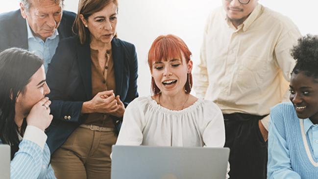 A multigenerational and multiracial team enthusiastically collaborates on a work assignment.